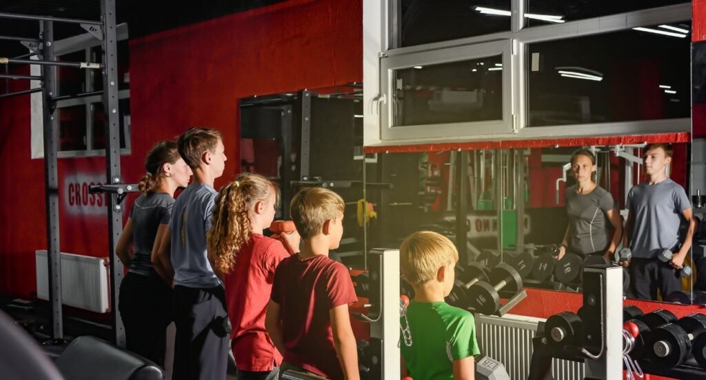Niños entrenando en un gimnasio con ejercicios adaptados para su edad.