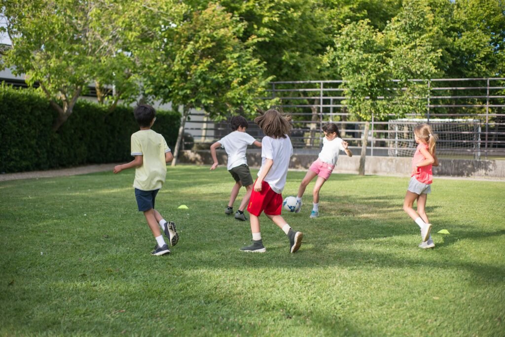 Group of kids having fun playing soccer on a grassy field on a sunny day.